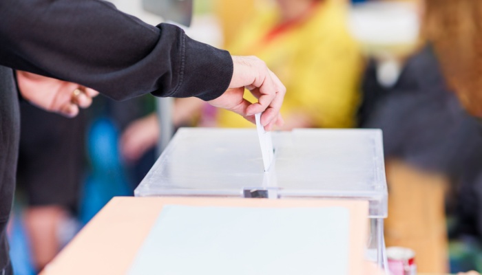 A man voting using a ballot box.