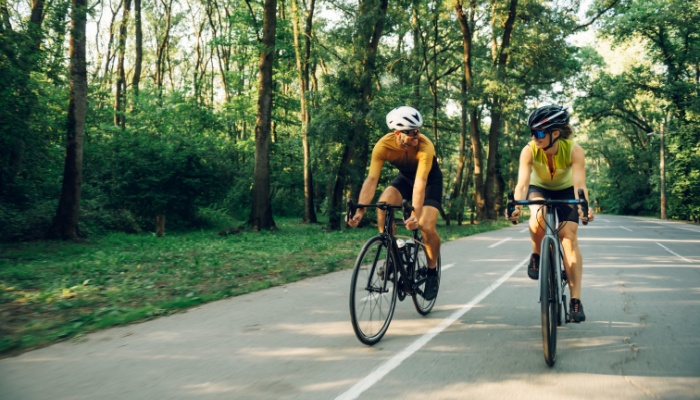 A couple cycling together on a road.