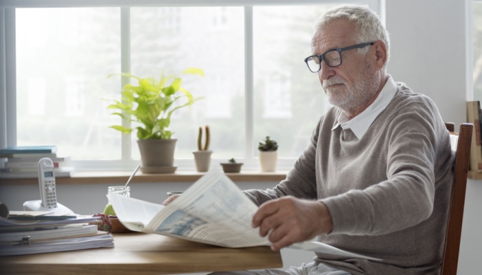 A man reading a newsletter at home.